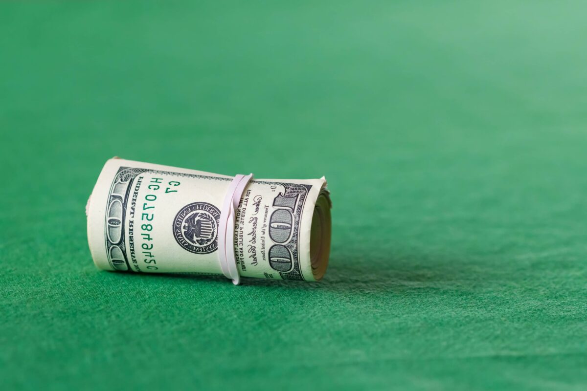 Rolled-up US dollar bills on a green surface, symbolizing financial markets and economic trends