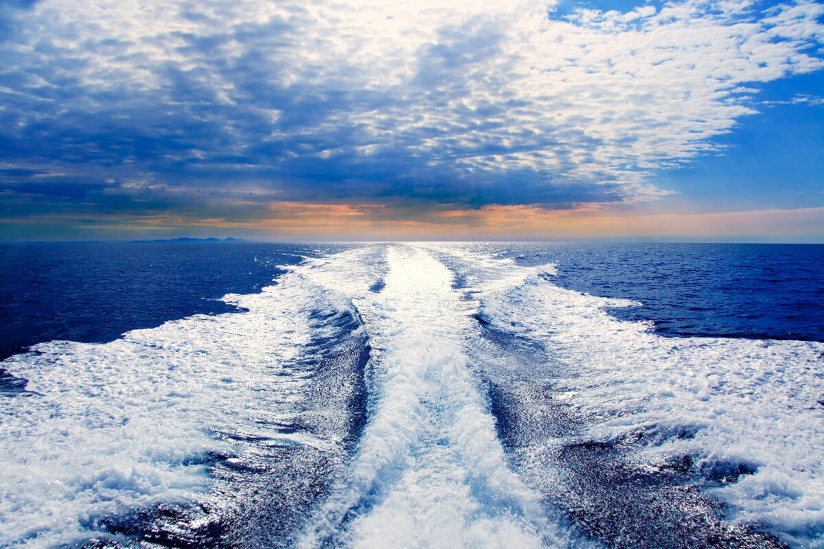 Ocean view with a yacht’s wake trailing behind, symbolizing a yacht charter adventure along the California coast